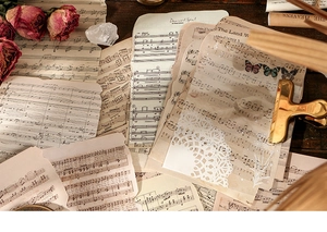 Detail of vintage scrapbooking papers with musical notes and floral motifs on dark wood