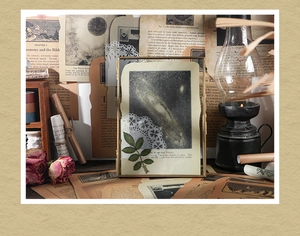 Macro detail of vintage galaxy art paper with real dried leaf and brass frame