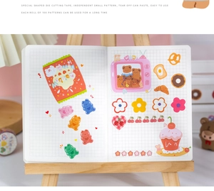 Macro shot of 100 die-cut cartoon bear and dessert stickers on a grid journal