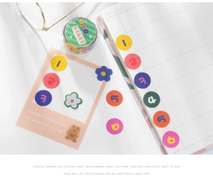 Detail of die-cut washi tape stickers with pastel numbers and floral patterns on paper