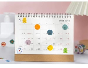 Detail of cute cartoon stickers on a minimalist kraft paper coil desktop calendar