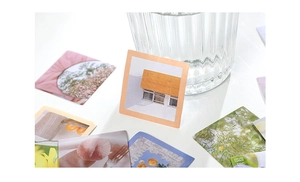 Detailed view of square aesthetic floral stickers on desk with glass cup background