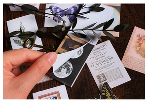 Detail of vintage washi sticker book with butterfly and botanical patterns on wood desk