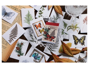 Vintage butterfly and plant stickers for journaling on a rustic wooden desk setup