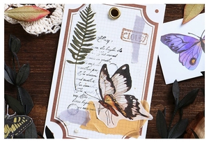 Close-up of vintage butterfly and fern washi stickers on a dark wooden background