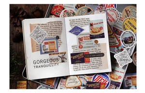 Detail of vintage traveler themed stickers and collage on a dark wood desk with pinecones