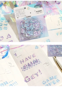 Detail of 3D holographic letter stickers on a grid journal with soft gradient colors