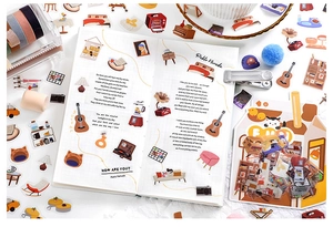 Detail shot of lifestyle PET stickers with vintage guitar and cat illustrations on a journal