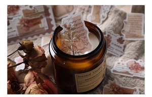 Détail d'une bougie parfumée vintage en verre ambré avec étiquettes botaniques décor