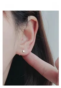 Close-up of minimalist hexagonal S925 sterling silver stud earring on a model ear