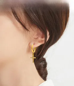 Close-up of a gold S925 silver hoop earring with a sparkling zircon cross pendant