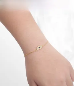 Detailed view of gold evil eye bracelet with blue and white zircons on female wrist