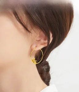 Détail d'une boucle d'oreille créole dorée avec un pendentif ange cupidon en 3D