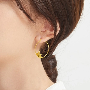 Créoles dorées chic avec pendentif ange miniature portées par un mannequin de mode