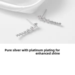 Macro shot of curved silver stud earrings with seven sparkling zircon stones and white gold finish