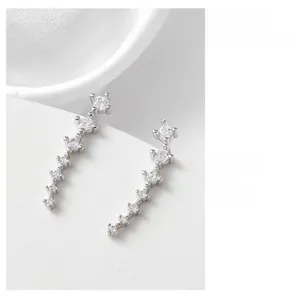 Detailed close-up of silver stud earrings featuring sparkling zircon stones and a curved design