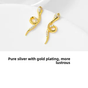 Detailed macro of gold-plated 925 sterling silver snake stud earrings with white zircons