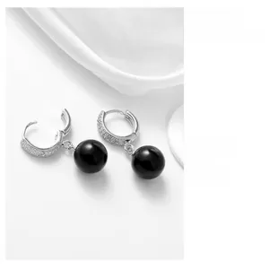 Détails macro des boucles d'oreilles en argent avec pavé de diamants et perles d'agate noire