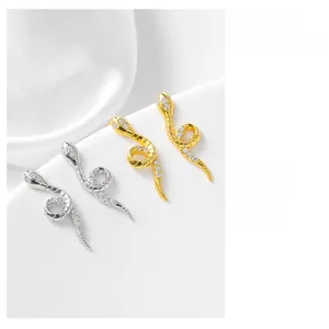 Macro detail of silver and gold snake-shaped stud earrings with sparkling zircon stones