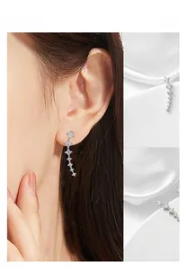 Macro shot of silver drop earrings with gradient zircon crystals on silk background