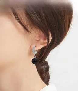 Gros plan de boucles d'oreilles créoles en argent S925 avec perles noires et zircons