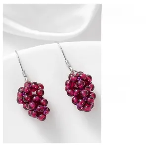 Detail of handmade garnet grape earrings with S925 silver hooks on white silk fabric