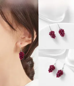 Detail of garnet grape cluster earrings with S925 silver hooks on white silk fabric