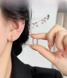 Detail shot of minimalist U-shaped hoop earrings in gold and silver on model