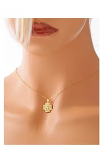 Close-up of a gold cross pendant necklace featuring religious relief on a model mannequin