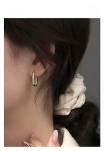 Gros plan de boucles d'oreilles dorées en forme de U portées par un mannequin chic