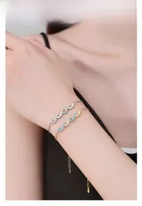 Close-up of wavy S925 silver and gold zircon bracelets worn together for a layered look