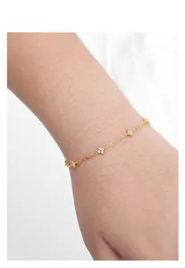 Close-up of elegant gold four-leaf clover bracelet with sparkling zircons on a wrist