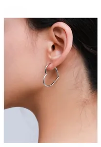Close-up of minimalist heart-shaped silver hoop earrings on female model