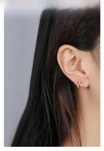 Detailed close-up of a golden balloon dog stud earring worn by a model for daily style