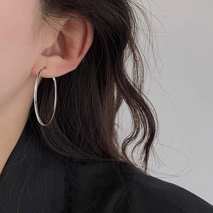 Aros grandes de plata pulida en una modelo para un look de moda minimalista