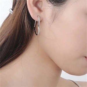 Minimalist S925 sterling silver heart hoop earrings worn by a model in a side view profile