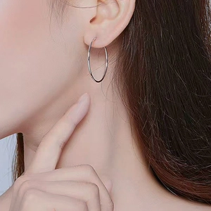 Grandes pendientes de aro minimalistas en plata mostrados en modelo para un estilo chic