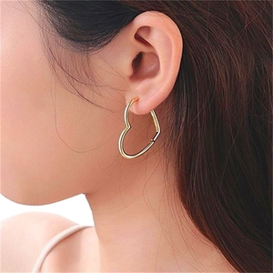 Minimalist S925 sterling silver heart-shaped hoop earrings worn on a model's ear