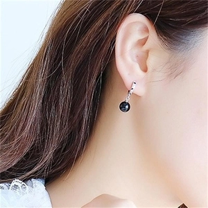 Detail shot of a woman wearing black agate bead earrings with polished silver hoops