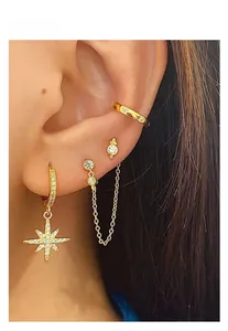 Close-up of gold star earrings set with zircon pendant and chain ear cuffs on model