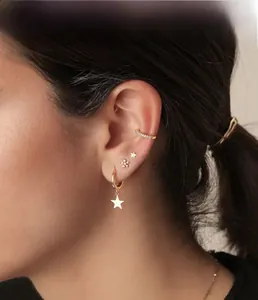 Close-up of gold star earrings and flower studs with pavé diamonds on a female model