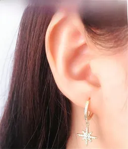 Close-up of gold starburst hoop earrings featuring white zircon pavé and minimalist design