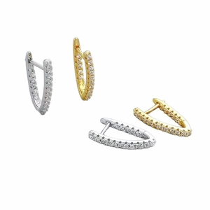 Detailed macro view of gold and silver V-shaped hoop earrings with cubic zirconia stones