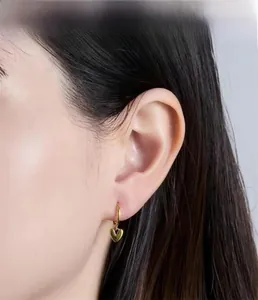 Minimalist gold heart hoop earrings worn by a model in a close-up side view profile
