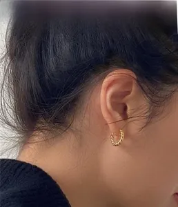 Detail view of 18K gold S925 sterling silver twisted hoop earring on model side profile