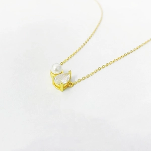 Detail of gold O-chain necklace featuring a round white pearl and pear-cut zircon pendant