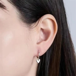 Minimalist 925 sterling silver heart hoop earrings worn by a model in a close-up shot