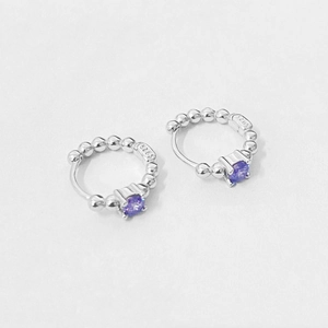 Close-up of S925 sterling silver beaded hoop earrings with a round purple gemstone