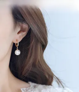 Close-up of gold pearl hoop earrings with sparkling cubic zirconia on a female model