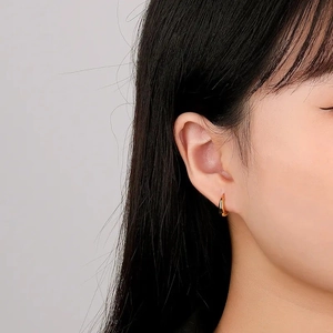 Classic gold hoop huggie earrings worn by model for a minimalist jewelry look